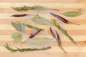 Dried bay leaves, red chili and rosemary on wooden surface