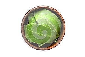 Dried bay leaves spice in wooden bowl, isolated on white background. Seasoning top view