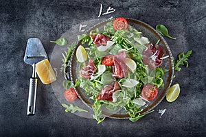 Dried beef bresaola. Salad bresaola arugula baby spinach tomatoes lime and cheese parmesan