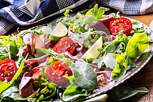 Dried beef bresaola. Salad bresaola arugula baby spinach tomatoes lime and cheese parmesan