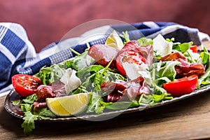 Dried beef bresaola. Salad bresaola arugula baby spinach tomatoes lime and cheese parmesan