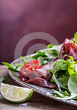 Dried beef bresaola. Salad bresaola arugula baby spinach tomatoes lime and cheese parmesan