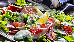 Dried beef bresaola. Salad bresaola arugula baby spinach tomatoes lime and cheese parmesan