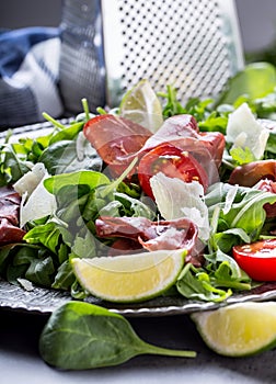 Dried beef bresaola. Salad bresaola arugula baby spinach tomatoes lime and cheese parmesan