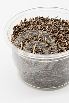 Dried black tea leaves in plastic cup isolated on white