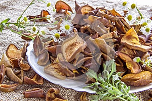 Dried brown pear slices white plate with white flowers. White daisy flowers and a green wormwood branch. Useful dry food. Edible s