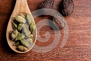 dried cardamom pods in spoon with nutmeg on wooden background, asia spice for cooking