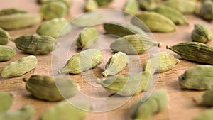 Dried cardamon seeds on a cutting wooden board.