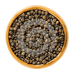 Dried cassia buds in wooden bowl over white