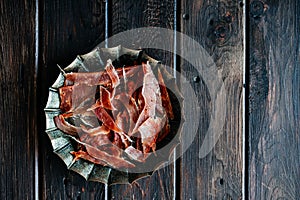 Dried chicken, dried poultry, cut into strips on a plate on a wooden background.