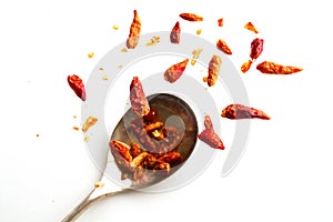 dried chili peppers jumping from a spoon, isolated on white, health concept capsaicin