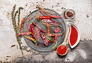 Dried chili peppers on a tray with crushed red pepper in the cups, with herbs.