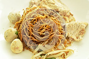 Dried Chinese yellow egg noodles topping slice boiled  pork and meatball dressing black sweet soybean sauce on dish with soup