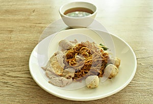 Dried Chinese yellow egg noodles topping slice boiled  pork and meatball dressing black sweet soybean sauce on dish with soup