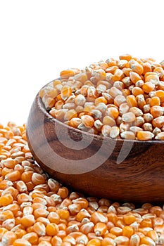 Dried corn kernels in wooden bowl isolated on white