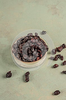 Dried cranberry fruit in a bowl on green
