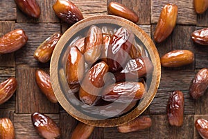 Dried date fruit in wooden bowl, top view