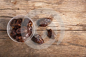 Dried date palm in cup on wooden floor.