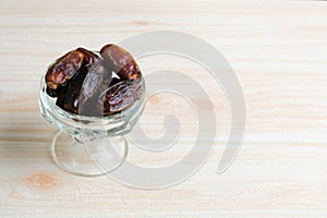 Dried dates in glass bowl on wooden backgrounder photo