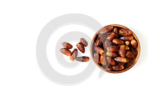 Dried dates in a wooden bowl isolated on white background. Copy space, top view, flat lay