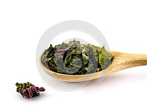 Dried Echinacea leaves and flowers lie in a wooden spoon on a white background