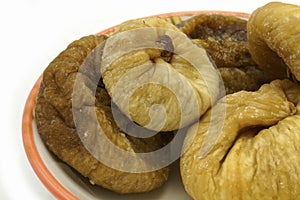 Dried figs on a ceramic saucer isolated on white background. Energy and fiber natural source. Dieting food photo