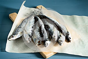 Dried fish in paper packaging. Salty fish. Blue nautical wooden background, closeup