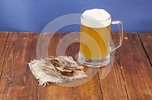 Dried fish in the shape of a straw with beer glass on wooden table. Salted fish delicacies on a table. Close-up