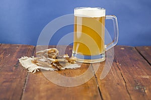 Dried fish in the shape of a straw with beer glass on wooden table. Salted fish delicacies on a table. Close-up