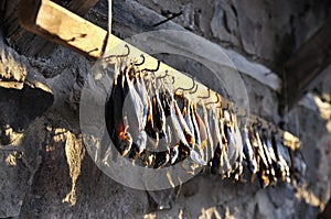 Dried fish on special fastening hangs along a stone wall