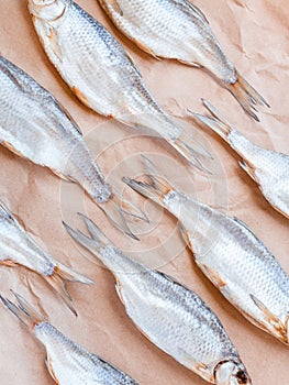 Dried fishes pattern with craft paper background. Vertical salted roach cover backdrop. Seafood snack poster decoration