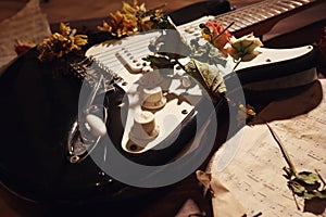 Dried flowers and electric guitar on old music notes closeup. Selective focus