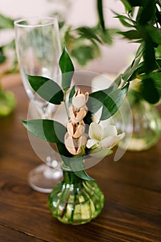 Dried flowers and green leaves in a glass green vase in the interior decor