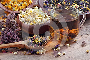 Dried flowers of medicinal chamomile. camomile flowers in a wooden bowl. cup of fresh chamomile tea. medicinal herbs