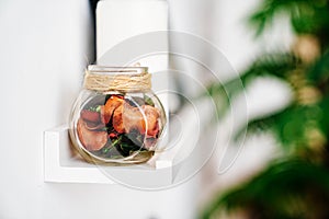 Dried flowers and perfumes in a glass jar on the shelf.