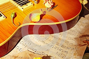 Dried flowers and vintage electric jazz guitar on old music notes closeup