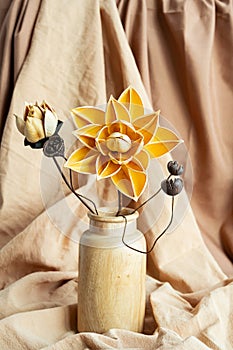 Dried flowers in wooden vase against draper. Monochromatic modern still life