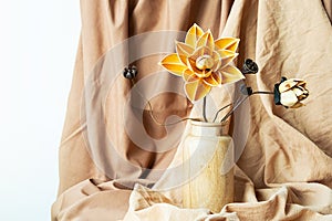 Dried flowers in wooden vase against draper. Monochromatic modern still life