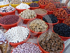 Dried fruit and sweets exposed in colored bowls in a market in Uzbekistan.