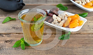 Dried fruit tray with tea glass with mint leaves on wooden background. Copy space
