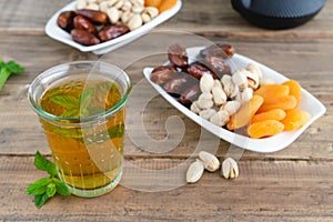 Dried fruit tray with tea glass on wooden background.