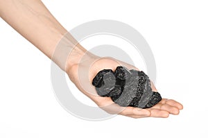 Dried fruits and cooking theme: man's hand holding a black Dried prunes isolated on a white background in studio