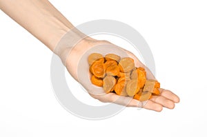 Dried fruits and meal preparation topic: human hand holding an orange dried apricots isolated on white background in studio