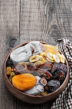 Dried fruits in wooden bowl on rustic background