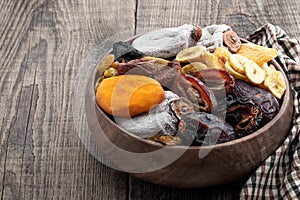 Dried fruits in wooden bowl on rustic wooden table