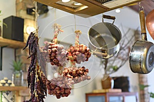 Dried garlic and red peppers hunging with saucepans in a kitchen