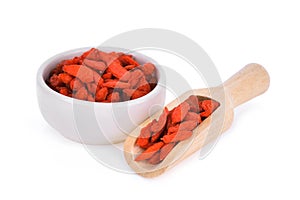 Dried goji berries in wooden scoop and white bowl isolated