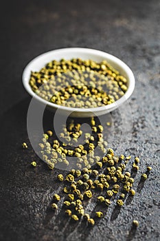 Dried green peppercorn. Dry green pepper spice on black table