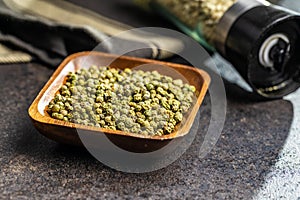Dried green peppercorn. Dry green pepper spice in bowl on black table