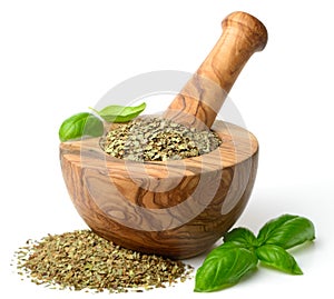 Dried herb, basil leaves in the wooden mortar, isolated on white
